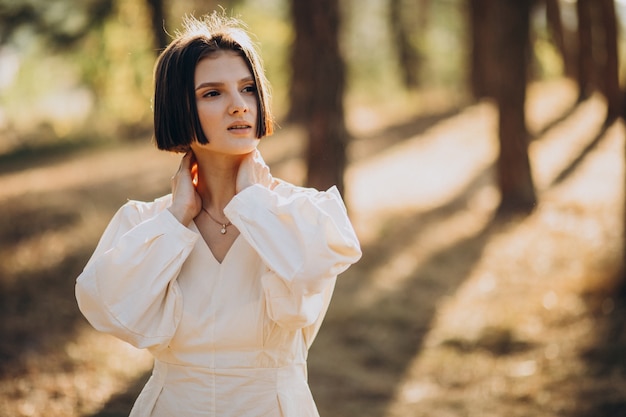 Young attractive woman in white dress in forest