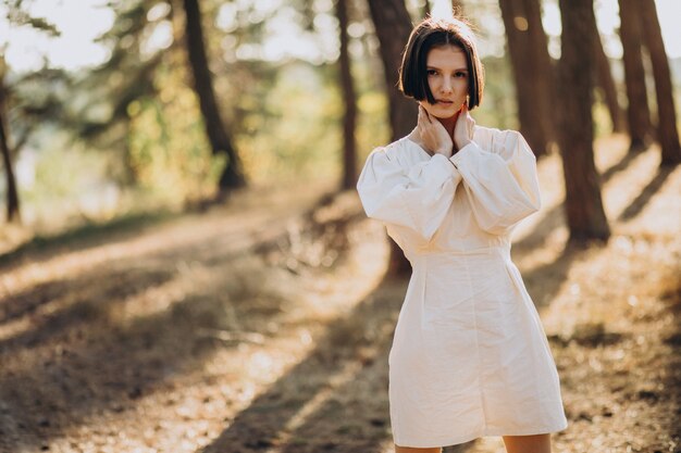 Young attractive woman in white dress in forest