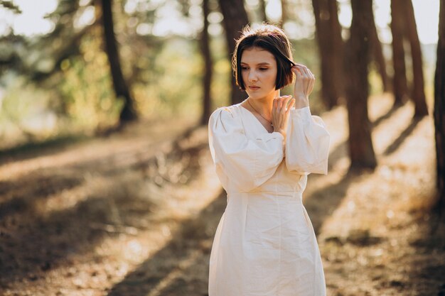Young attractive woman in white dress in forest