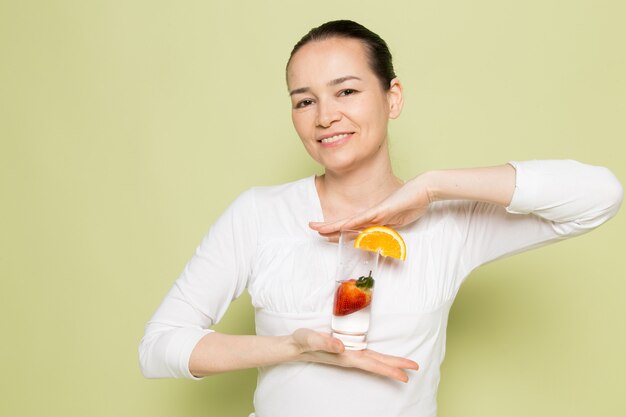 Молодая привлекательная женщина в белой рубашке, держа стакан с молоком и фруктами