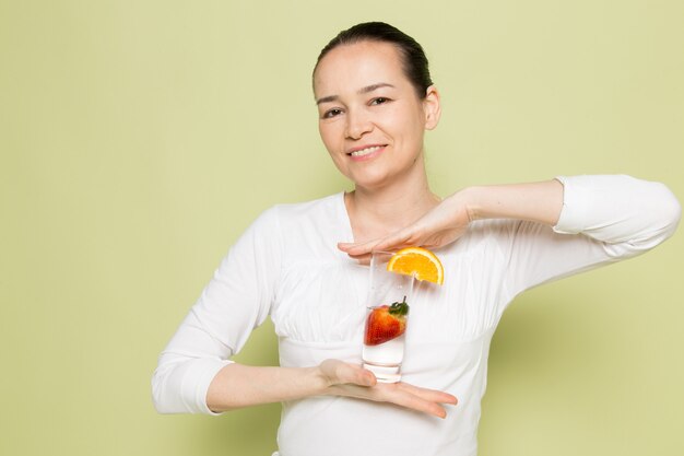 Young attractive woman in white shirt holding glass with milk and fruits