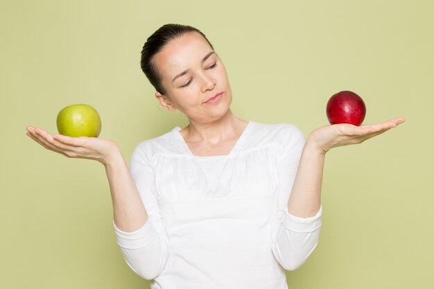 Young attractive woman in white shirt holding green and red apples