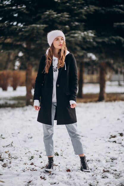 Молодая привлекательная женщина в зимнем парке в милой шляпе