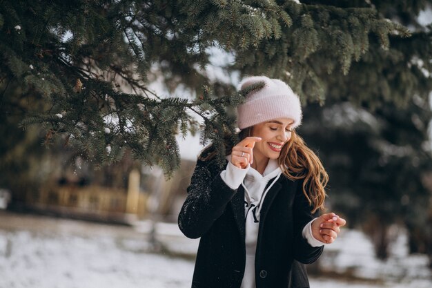 かわいい帽子の冬の公園で若い魅力的な女性