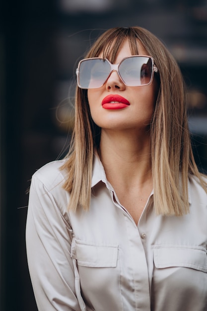 Free photo young attractive woman with red lips posing in the street