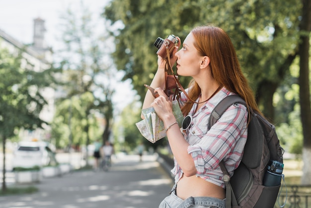 Free photo young backpacker taking picture in park