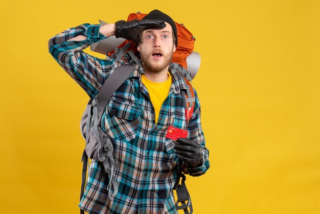 young backpacker with black hat holding credit card observing