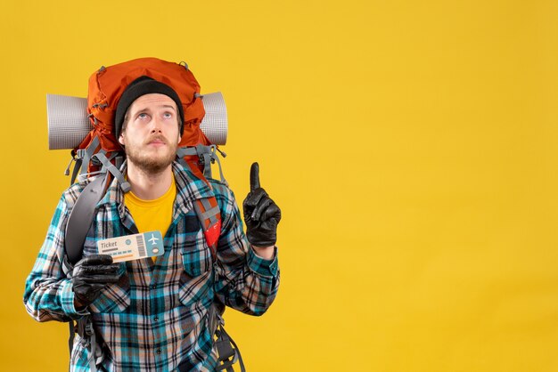 young backpacker with black hat holding travel ticket pointing ceiling