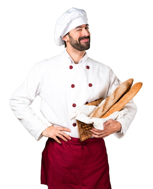 Бесплатное фото Молодой пекарь, держащий хлеб и подмигивая
