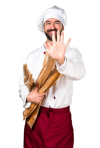 Young baker holding some bread and counting five