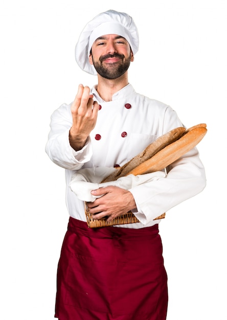 Free photo young baker holding some bread doing coming gesture