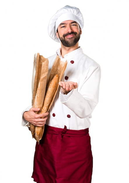 Young baker holding some bread and holding something