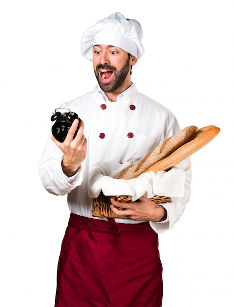 Young baker holding some bread and holding vintage clock