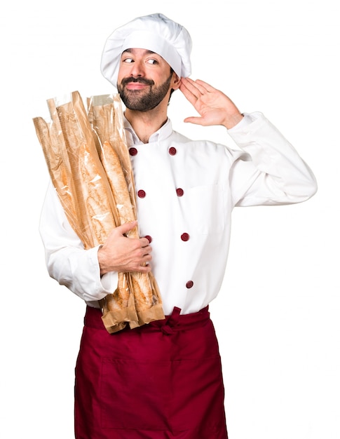 Young baker holding some bread and listening something