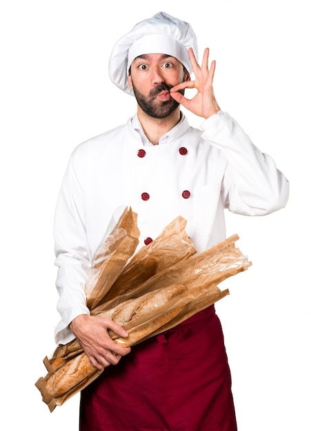 Young baker holding some bread and making silence gesture