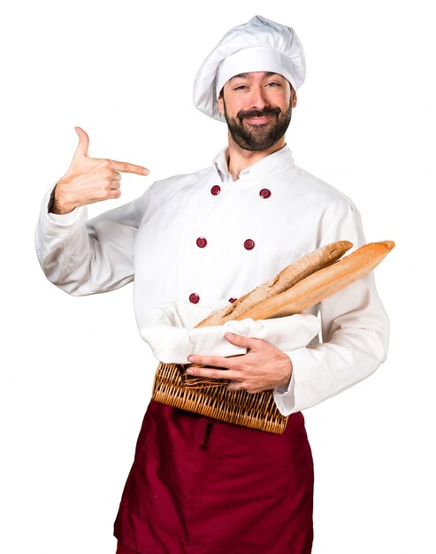 Young baker holding some bread proud of himself