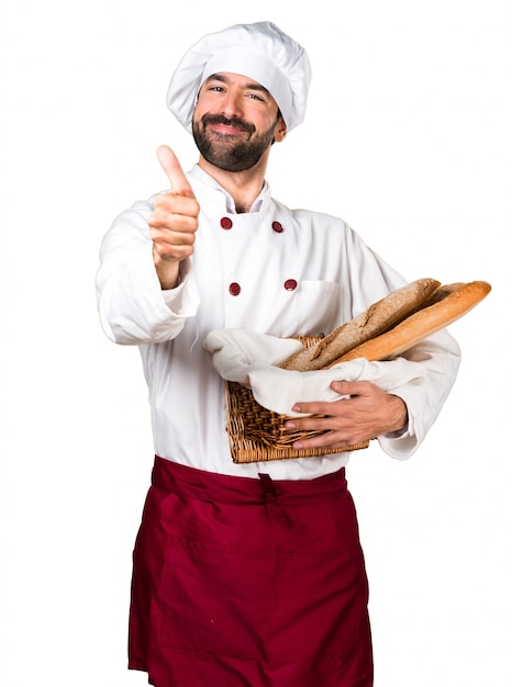 Young baker holding some bread and with thumb up