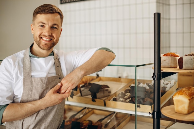 Free photo young baker standing by the counter in a bake house