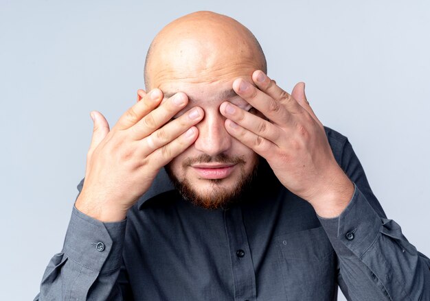 Young bald call center man closing eyes with hands isolated on white background