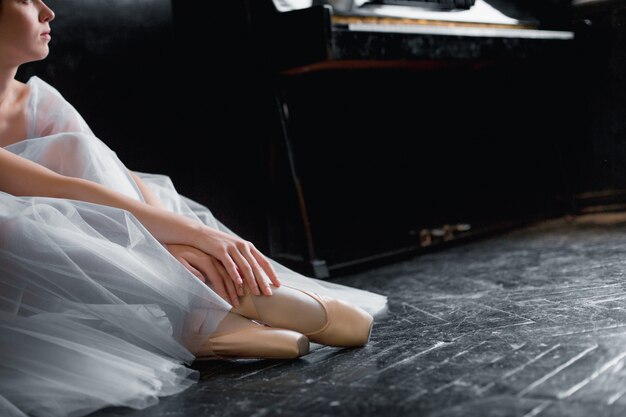 Young ballerina dancing, closeup on legs and shoes, sitting in pointe shooses