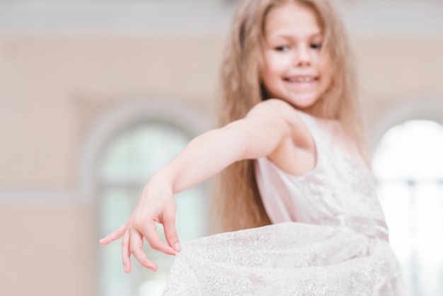 Young ballerina girl with long blonde hair holding her elegance dress