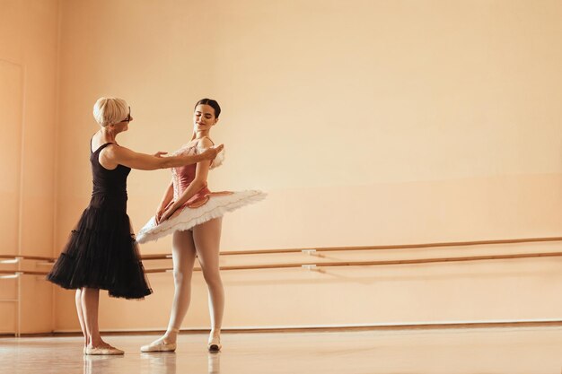 Молодая балерина в сценическом костюме репетирует со своим зрелым инструктором