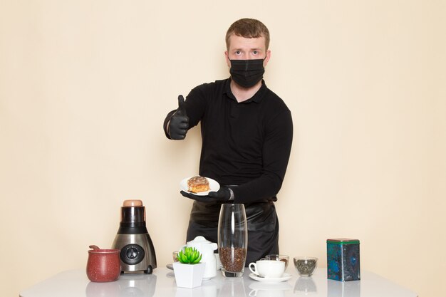白の黒い滅菌マスクを身に着けている成分とコーヒー機器茶色のコーヒー種子と黒の作業服の若いバリスタ