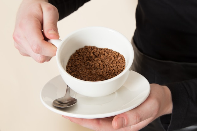 Free photo young barista in black working suit with ingredients and coffee equipment brown coffee seeds on white