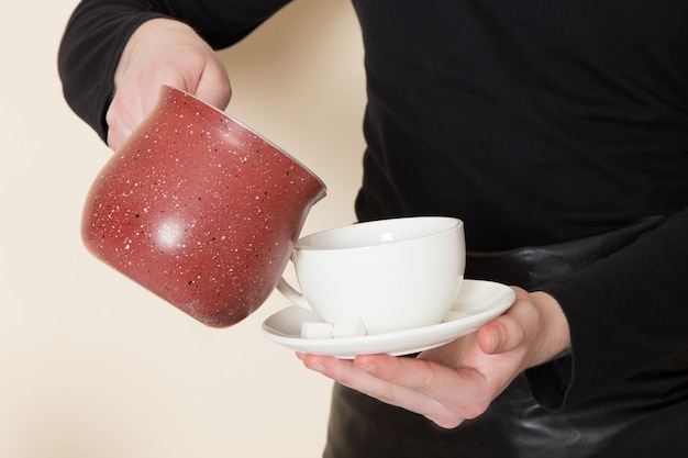 Free photo young barista in black working suit with ingredients and coffee equipment brown coffee seeds on white