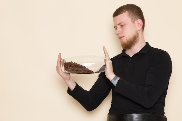 young barista in black working suit with ingredients and coffee equipment brown coffee seeds on white