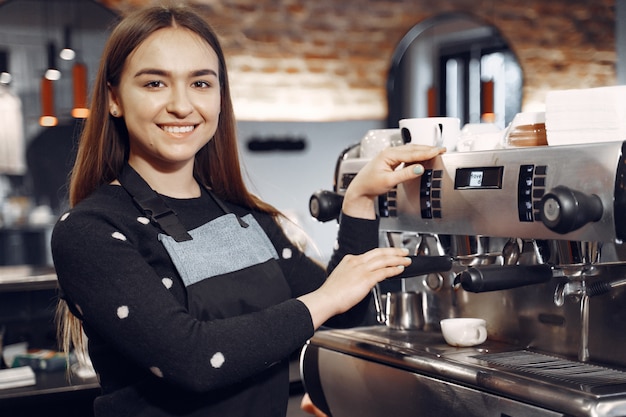 Foto gratuita la giovane ragazza di barista fa il caffè e sorride