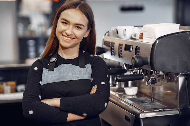 Foto gratuita la giovane ragazza di barista fa il caffè e sorride