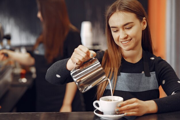 Молодая девушка бариста делает кофе и улыбается