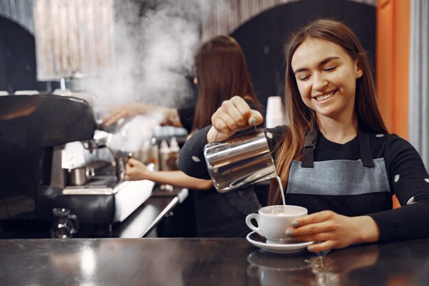 Молодая девушка бариста делает кофе и улыбается