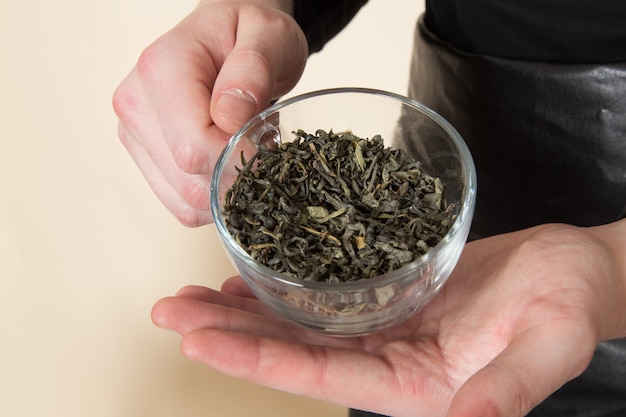 young barista holding glass with dried tea