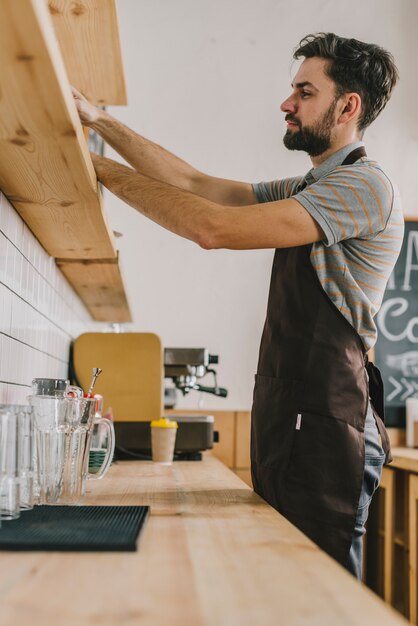 Young bartender arranging jars