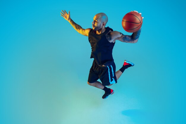 スポーツウェアのトレーニング、アクションの練習、ネオンの光の青い壁の動きを身に着けているチームの若いバスケットボール選手