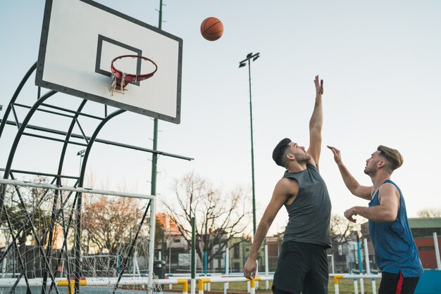 屋外のコートで1対1で遊ぶ若いバスケットボール選手。スポーツとバスケットボールのコンセプトです。