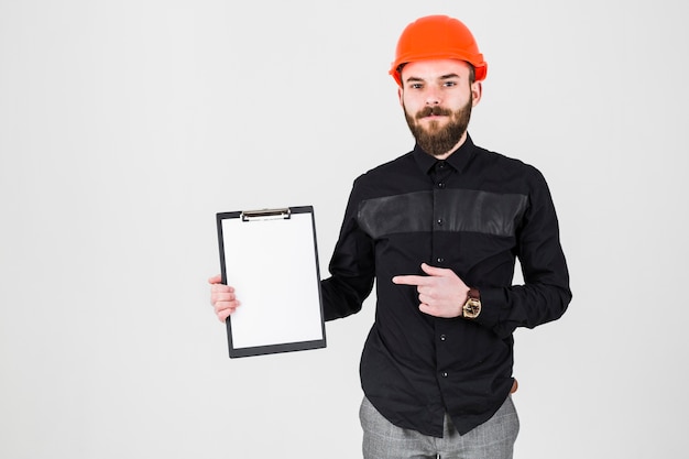 Young beard architect pointing at clipboard isolated over white backdrop