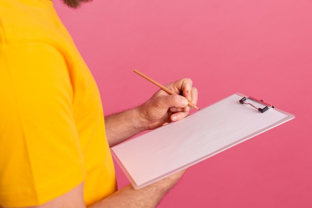 Young bearded employee man casual wear taking notes against a pink background