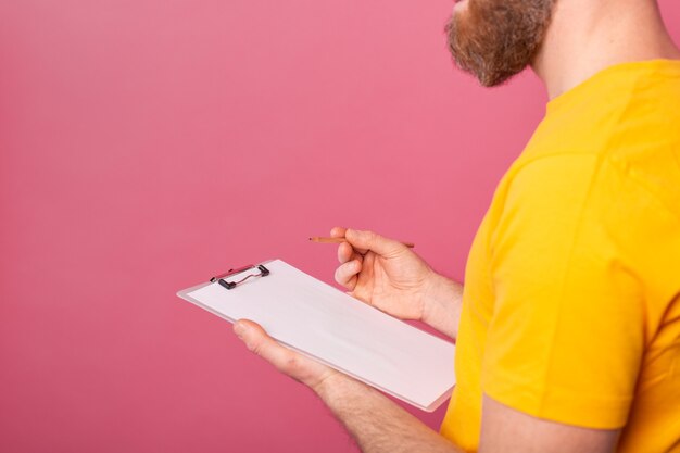 젊은 수염 직원 남자 캐주얼 분홍색 배경에 메모를 복용