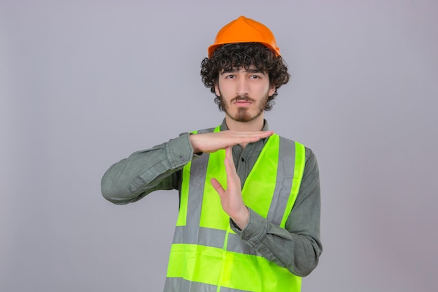 Молодой бородатый красивый инженер, выглядящий перегруженным, делает тайм-аут с руками, стоящими над изолированной белой стеной
