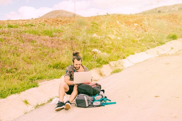 Free photo young bearded male working on laptop in trip