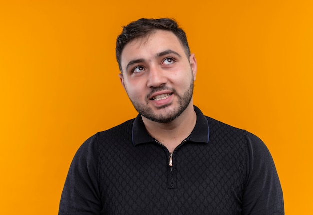 Free photo young bearded man in black shirt  looking aside confused