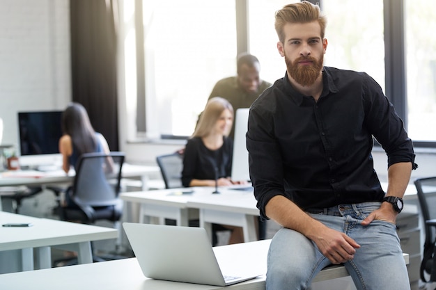 Young bearded man sitting on his desk in an office