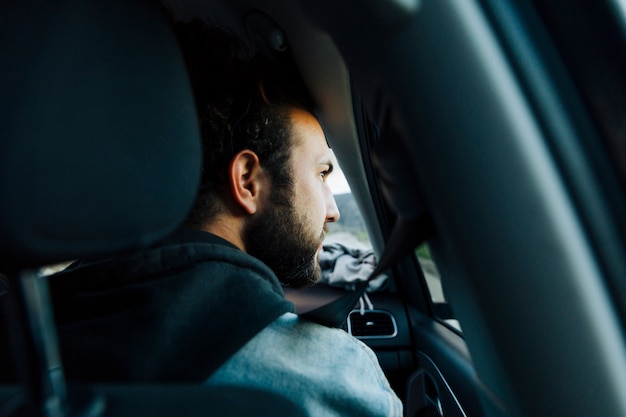 Free photo young bearded man traveling by car