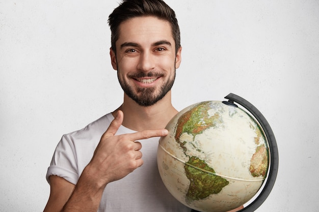 Free photo young bearded man with white t-shirt and globe