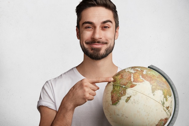 Young bearded man with white T-shirt and globe