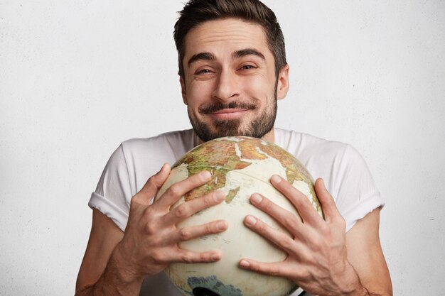 Young bearded man with white T-shirt and globe