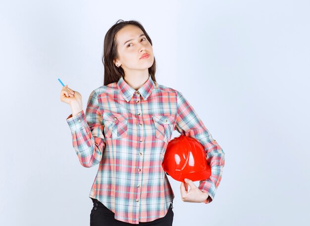 Young beautiful architect woman holding security helmet with pen .